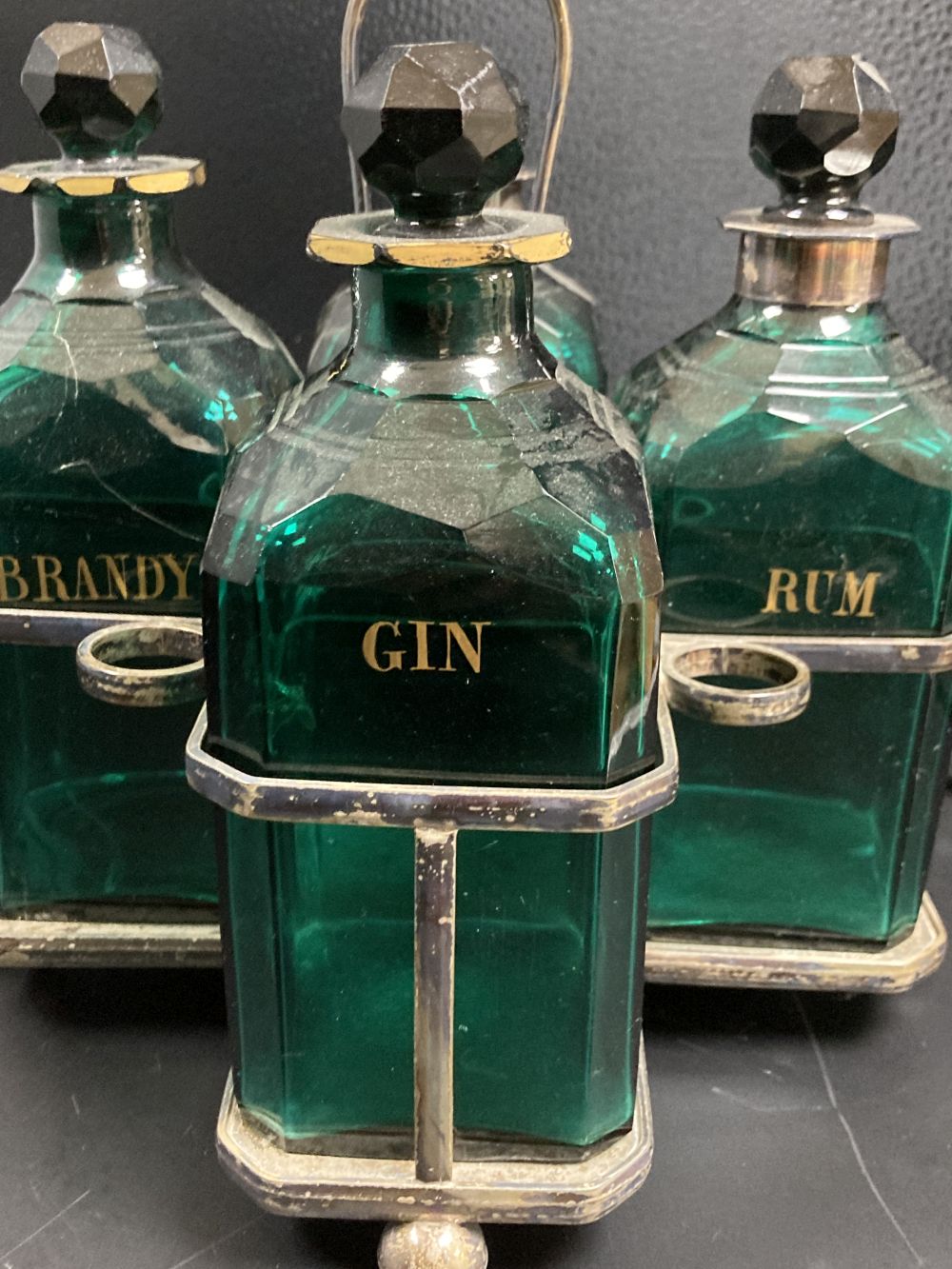 A set of four Victorian cut green glass spirit bottles, in a plated frame, 28cm,